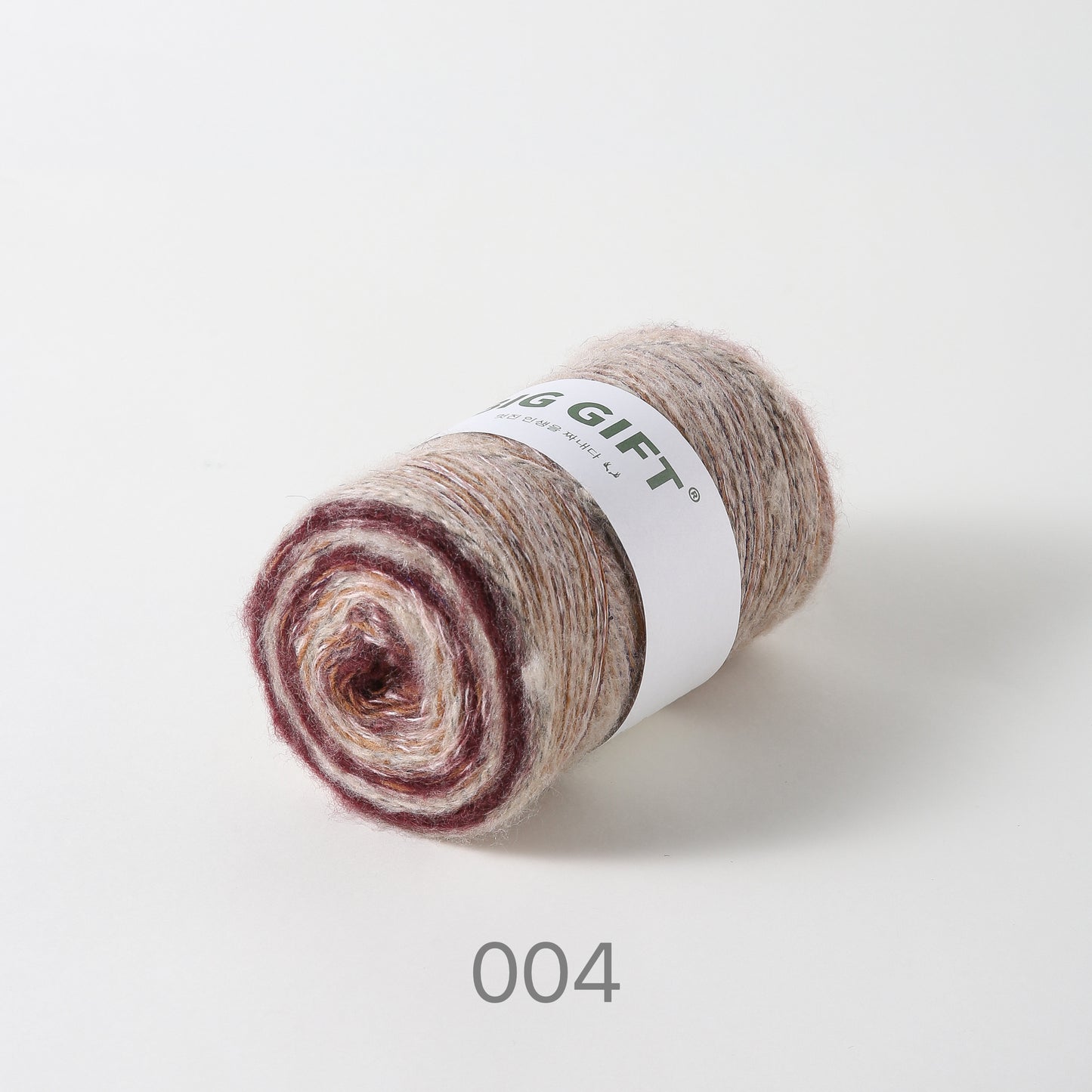 Artisan wool blend for crochet yarn in neutral and maroon tones rolled in a ball with label