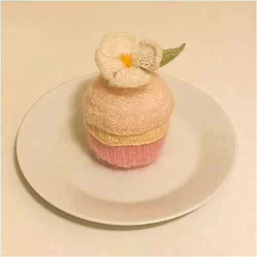 Handcrafted knitted cupcake pattern with red strawberry and green leaf on pink frosting from The Knit Krazy