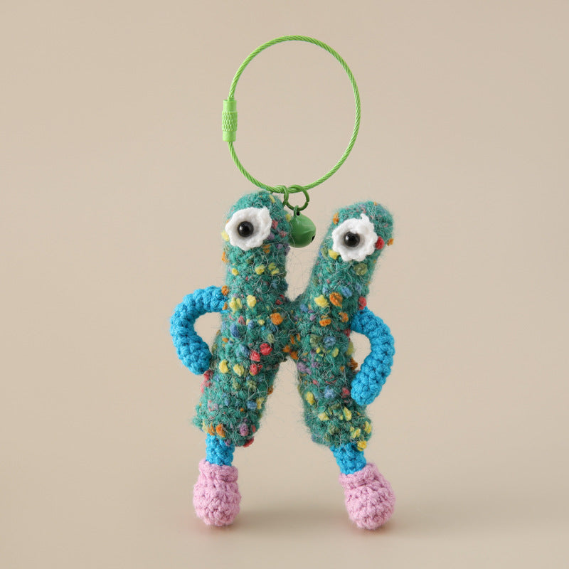 Colorful yarn key decoration shaped like a quirky character with blue arms and pink feet