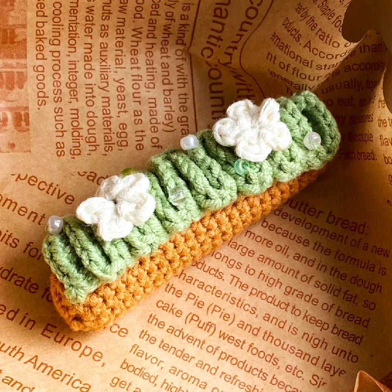 Crochet eclair pattern beginner kit with green and tan yarn decorated with white flowers and beads