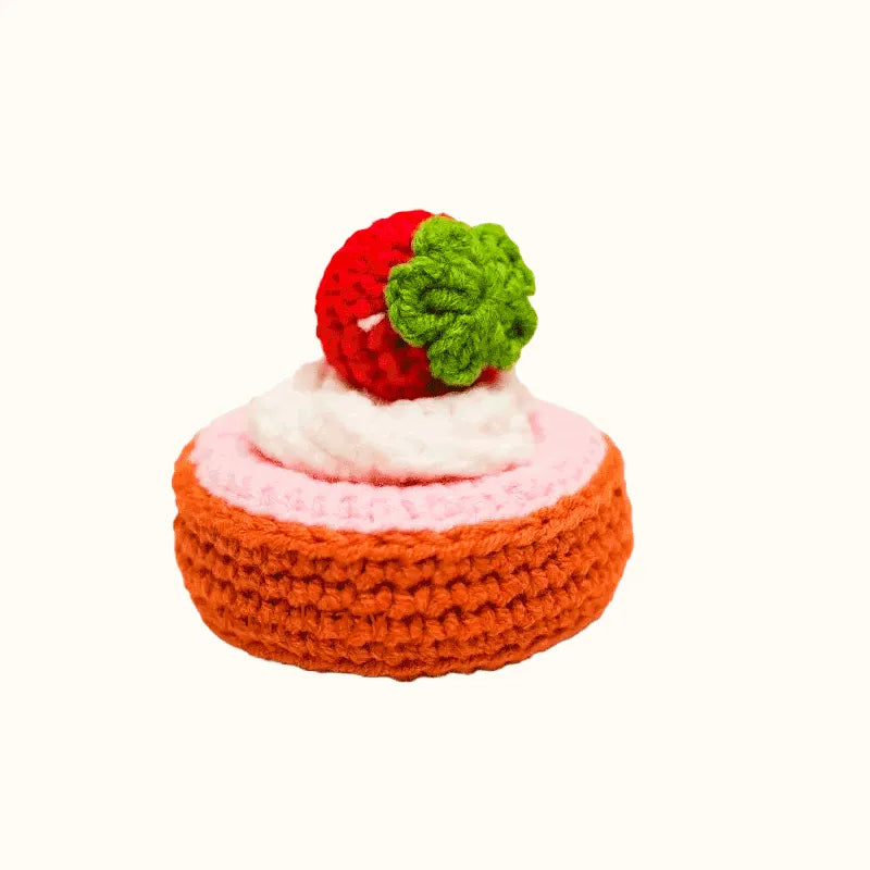 Handcrafted crochet French tart pattern featuring a red strawberry and green leaves on pink and orange base