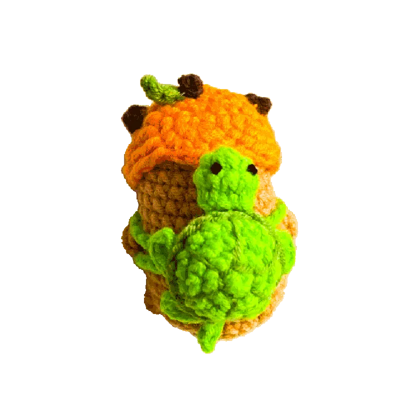 Handmade crochet mini capybara pattern with orange body and green turtle accessory