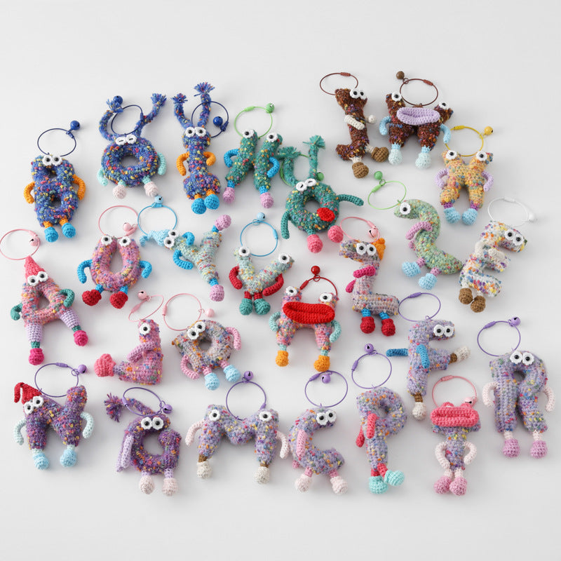 Colorful crocheted personalized letter F keychain with eyes among various handmade letter keychains