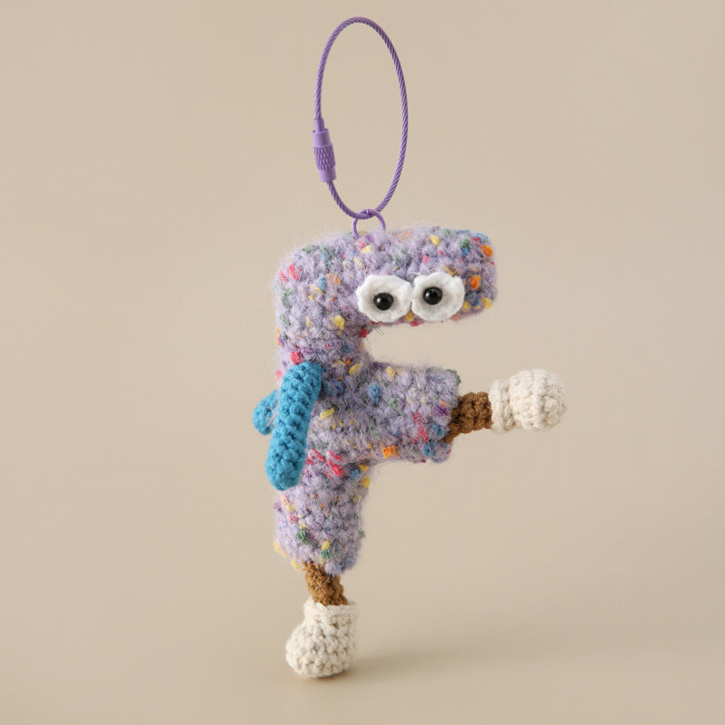 Colorful crocheted personalized letter F keychain with eyes and limbs hanging on a purple loop