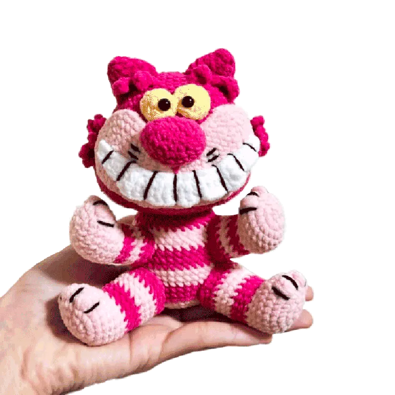 Hand holding a colorful crocheted Cheshire Cat toy made using a free crochet cheshire cat pattern