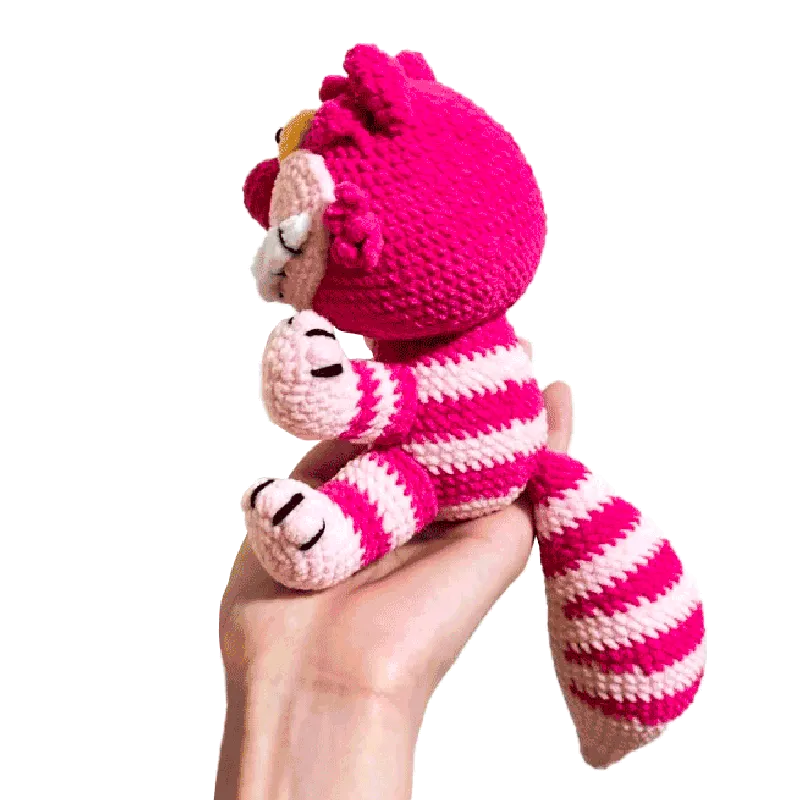Hand holding a pink and white striped crocheted Cheshire cat toy from free crochet cheshire cat pattern