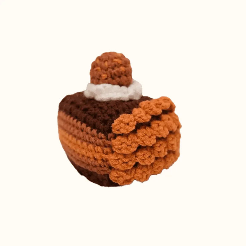 Handcrafted crochet chocolate cake pattern with layered brown and tan yarn and a dollop of cream on top