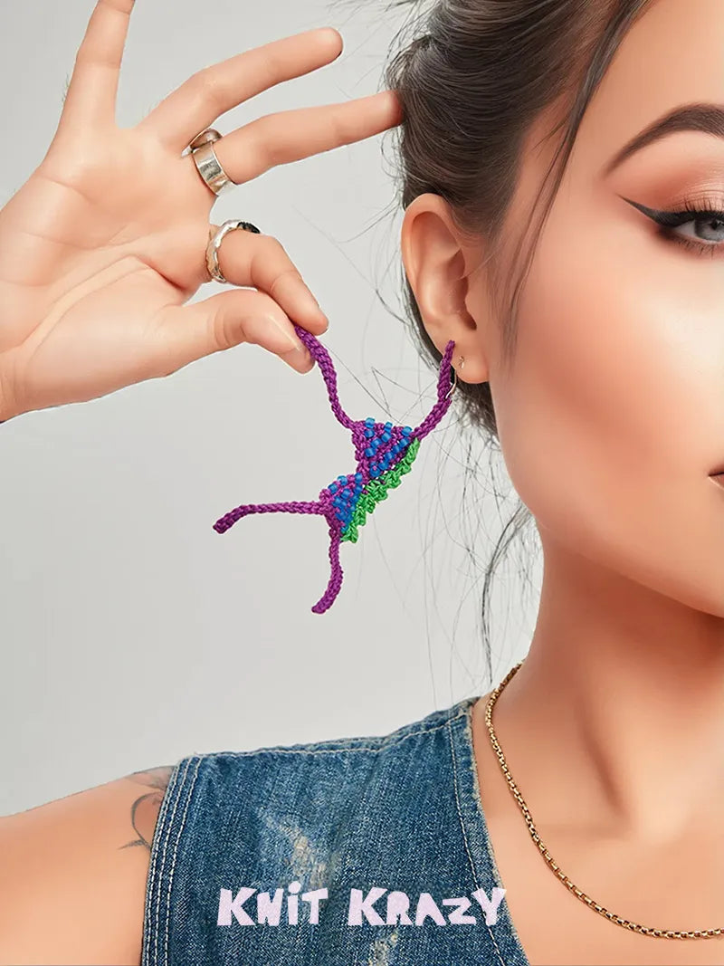 Close-up of a woman wearing colorful handmade crochet earrings with purple, blue, and green yarn