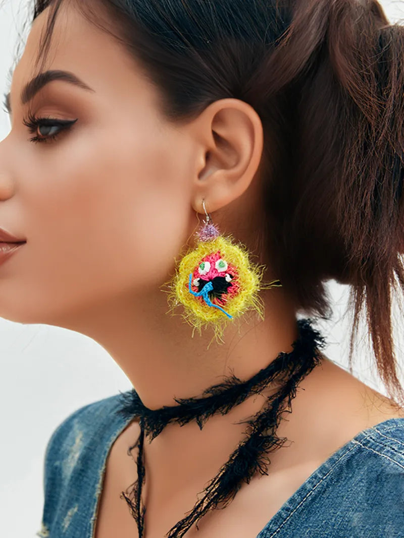Handmade floral snake earrings in bright yellow worn by woman with dark hair and denim top