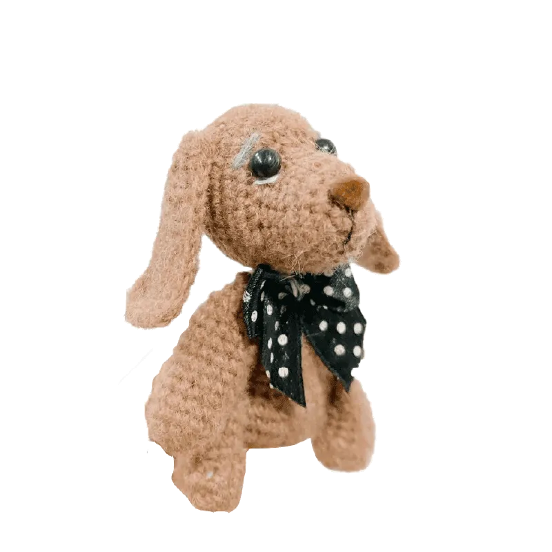 Handmade mini crochet puppy pattern in light brown yarn with black and white polka dot bow