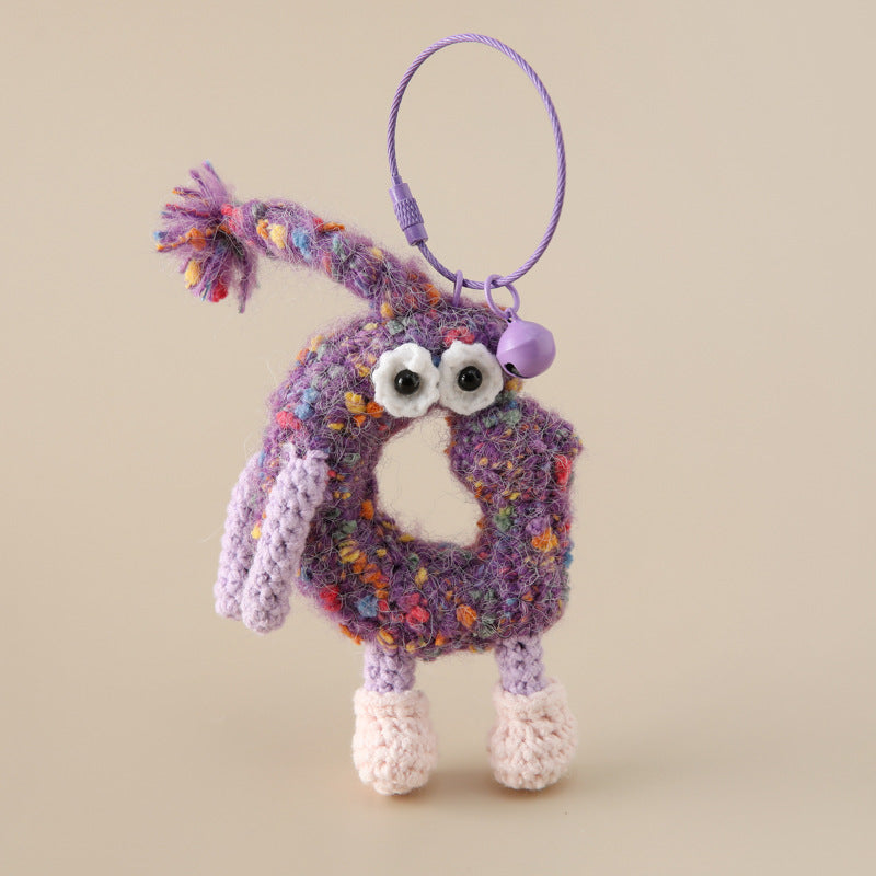 Colorful crocheted letter keychain with googly eyes and purple bell attached