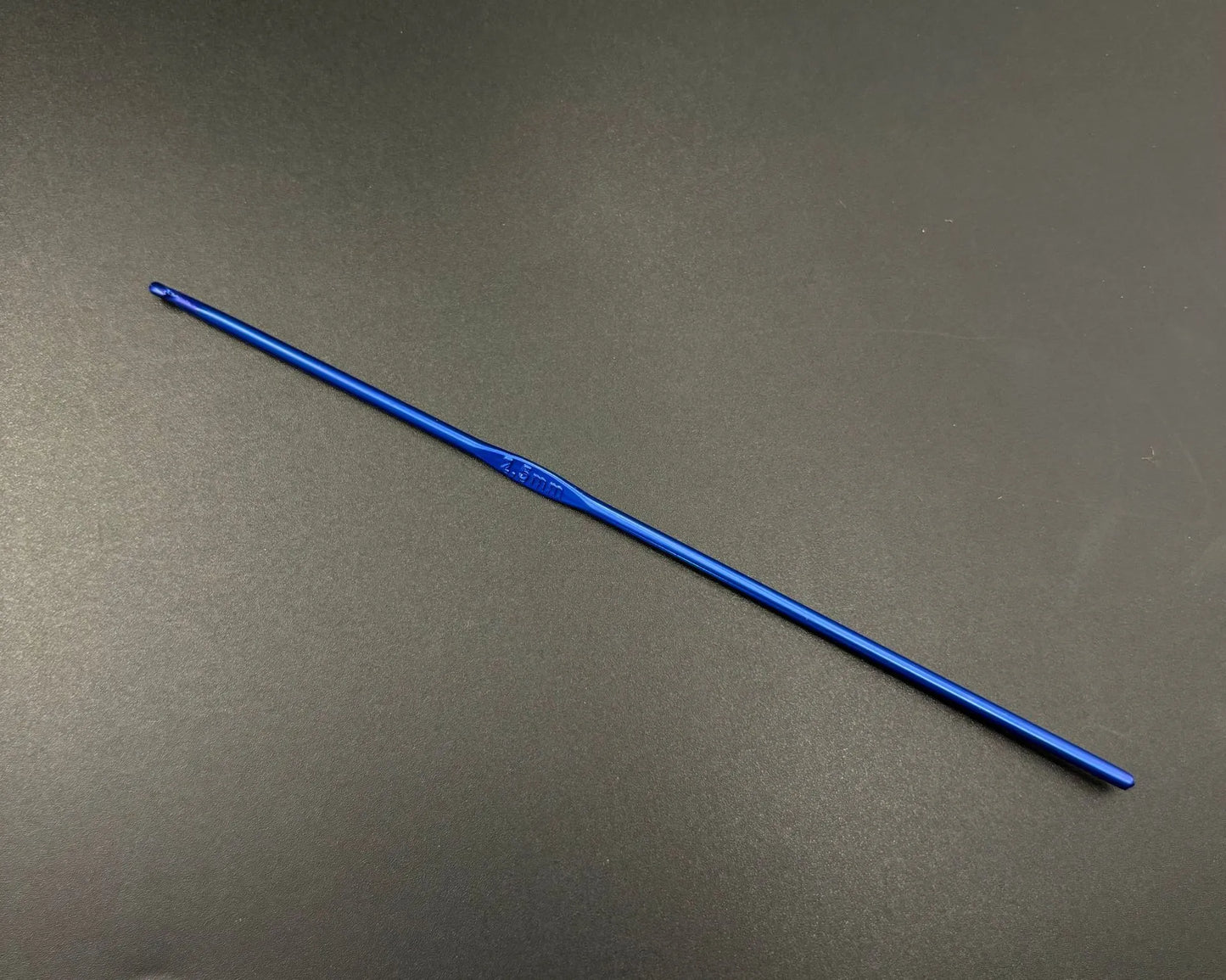 Single blue aluminum crochet hook from rainbow aluminum crochet hooks set on black background