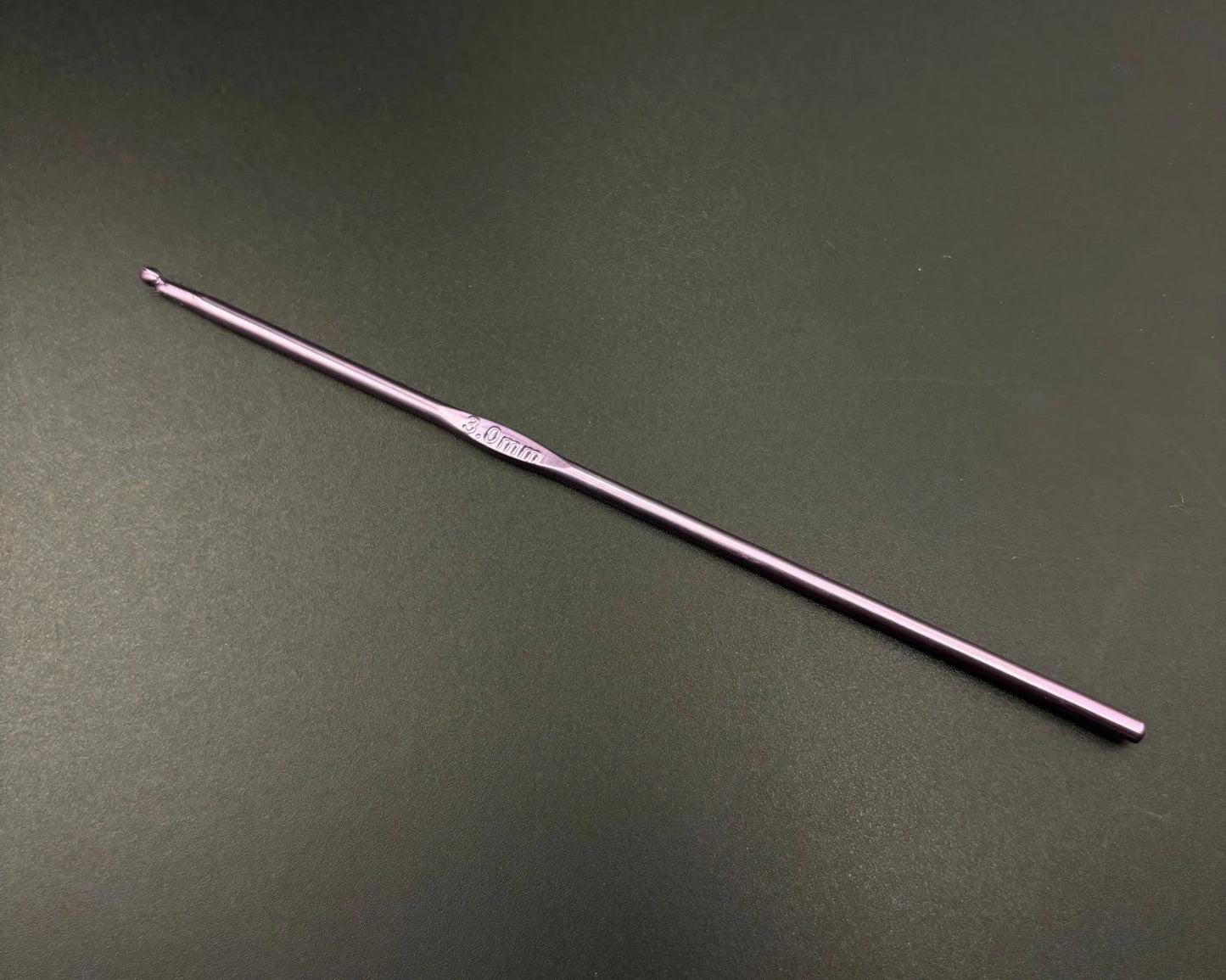 Single lavender crochet hook from rainbow aluminum crochet hooks set on black background