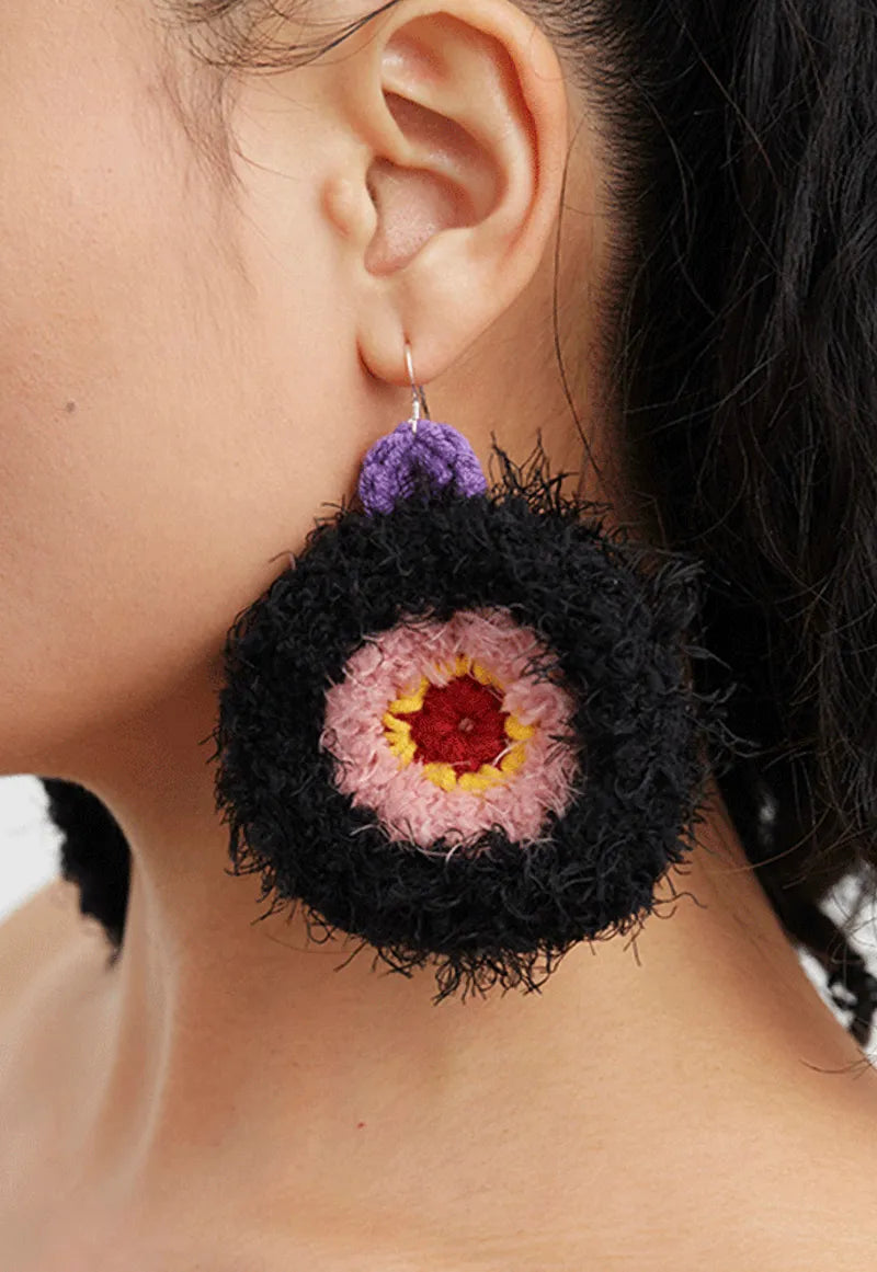 Unique handmade earrings featuring a colorful fuzzy circular design hanging from ear