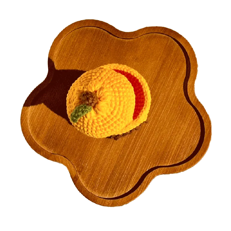 Handmade crochet capybara storage box pattern in yellow displayed on a wooden tray