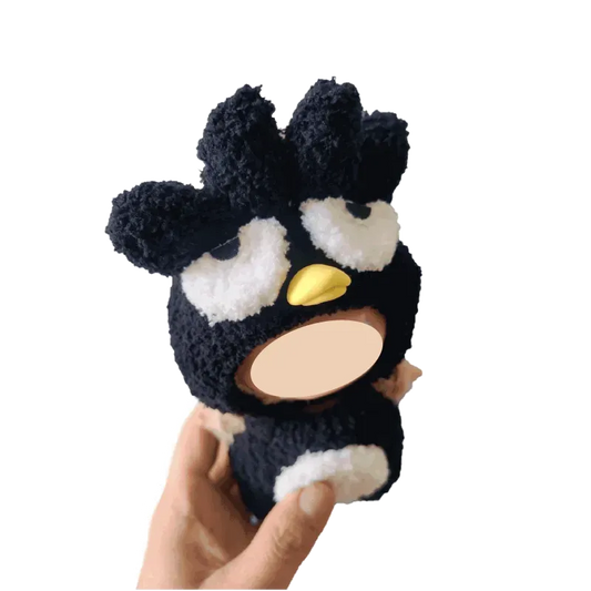 Hand holding a black penguin plush doll costume with white eyes and yellow beak soft fabric