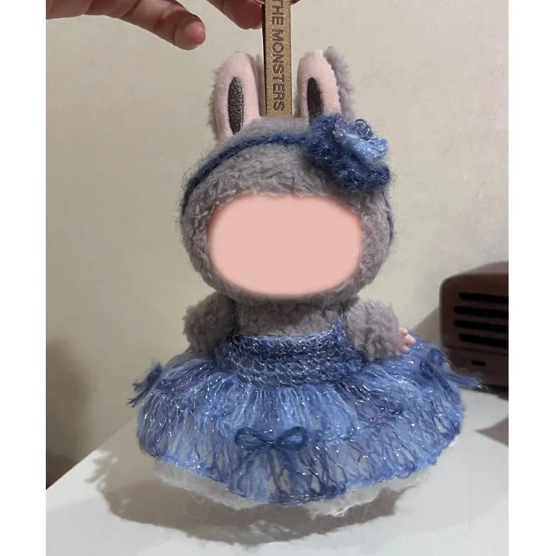 Handmade crochet doll wearing a blue crochet doll dress pattern featuring a flower headband and fluffy skirt