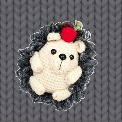 Cute handmade crochet hedgehog with black eyes and red berry on head using crochet hedgehog pattern
