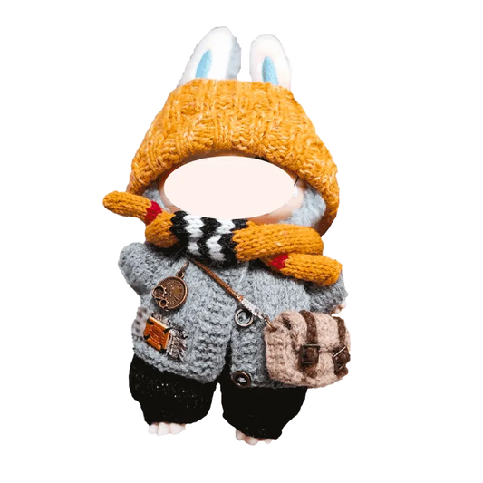 Handmade knitted doll wearing a yellow hat with bunny ears, gray sweater, scarf, and small satchel bag