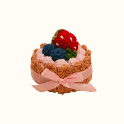 Handmade crochet biscuit cake topped with crocheted strawberries and blueberries with pink ribbon crochet biscuit cake pattern