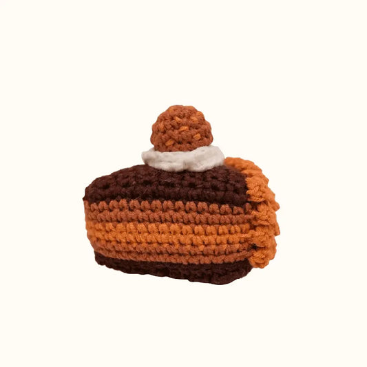 Crochet chocolate cake pattern featuring a brown and orange striped slice with white and brown topping