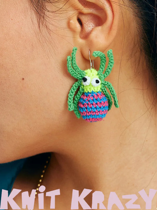 Handmade spider web earrings crocheted in bright green and blue colors worn on ear