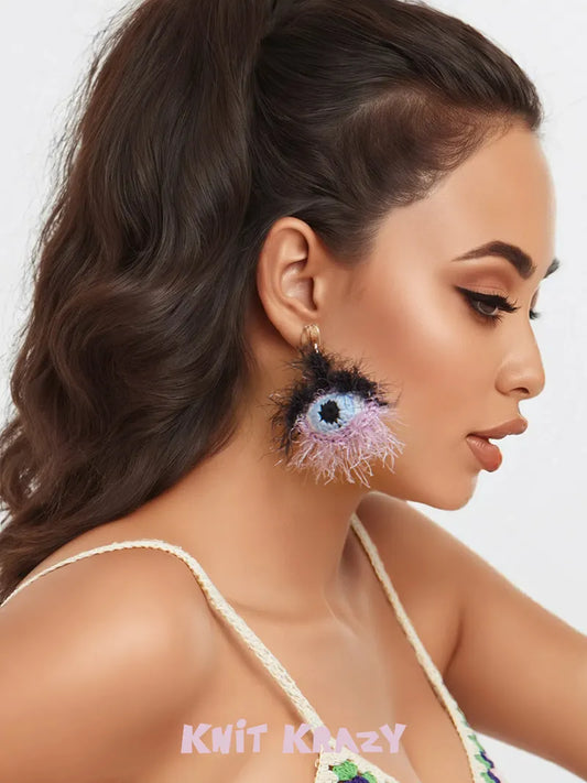 Handmade surrealist eye earrings in black and purple worn by a woman with long brown hair