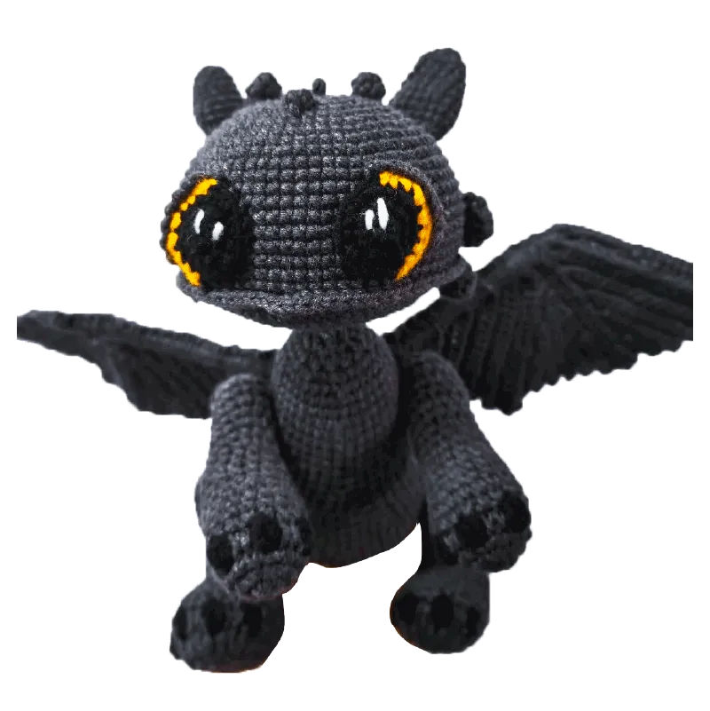 Handmade Toothless crochet gift featuring a black dragon with large orange and black eyes and spread wings