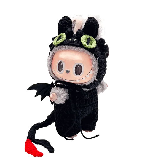Cute doll wearing a black and gray night dragon crochet pattern costume with green eyes and red tail tip