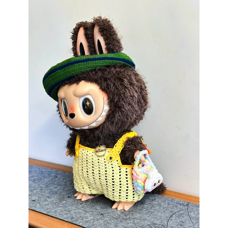 Cute toy figure wearing green headband and yellow Zimomo crochet outfit pattern overalls with plush brown fur